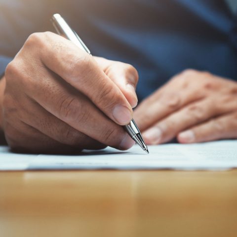 businessman writing on paper report in office